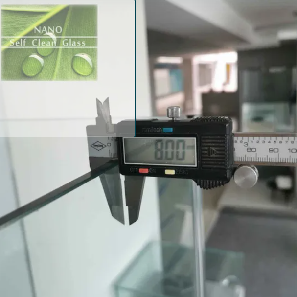 Digital caliper measuring a glass panel with a Nano Self Clean Glass sign in the background.