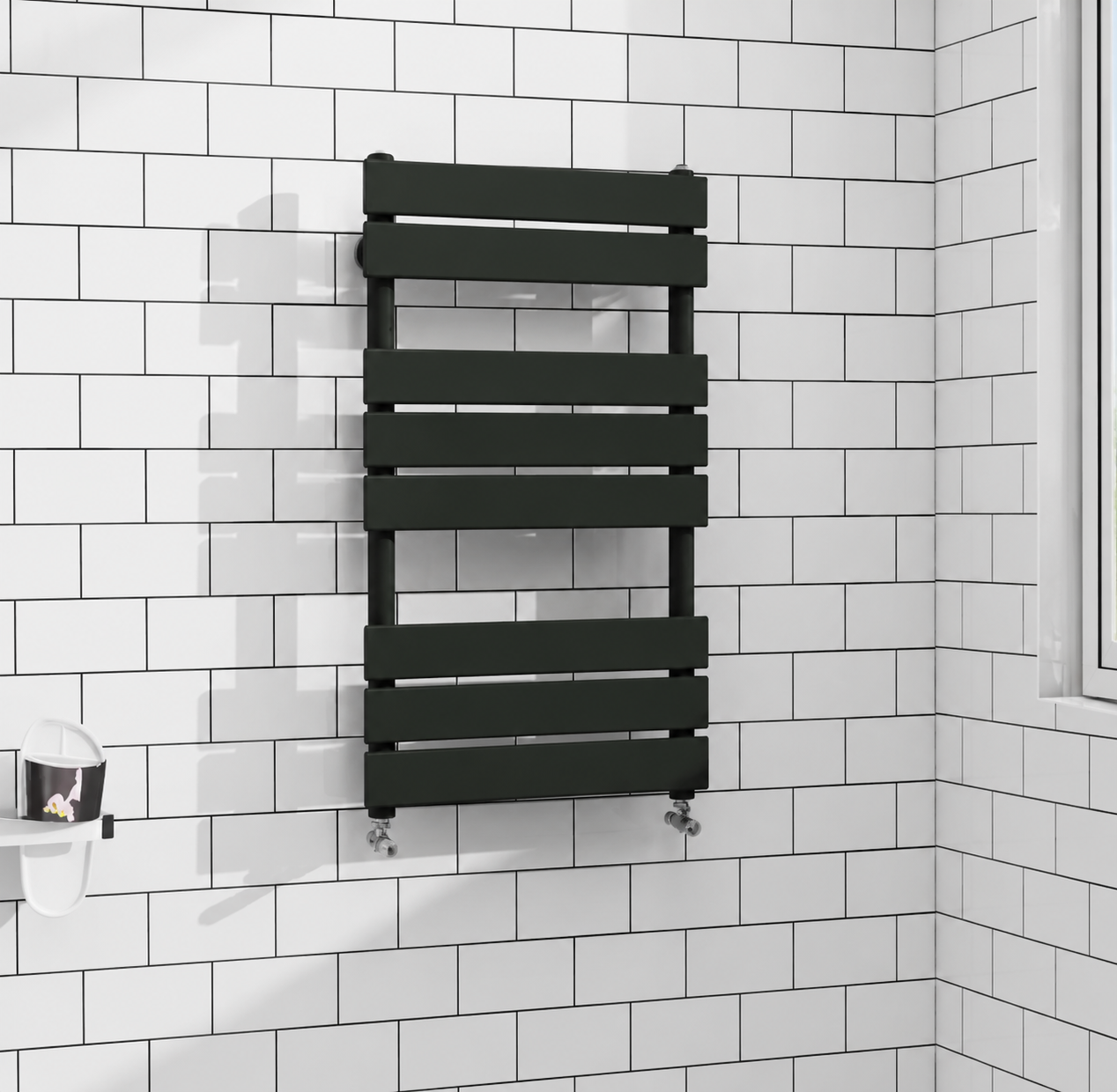 Black flat panel heated towel rail radiator fitted against white brick tiles with black grout in modern bathroom