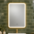 K LIGHT OTTONE brushed brass LED bathroom mirror illuminated against green brick tiles
