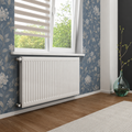 K Rad Type 21 white central heating radiator, 600mm x 1500mm, wall mounted beneath a window with blue floral wallpaper and wooden flooring.