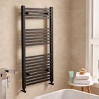 K Warm square matt black towel rail in a warm stone tiled bathroom